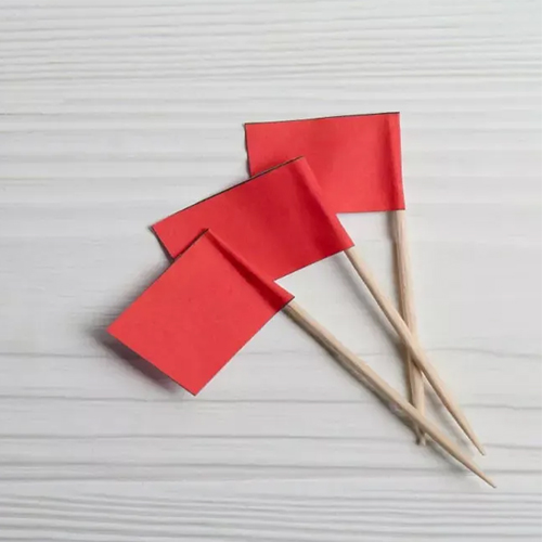 A row of bright red flags on a table symbolizes financial warning signs or money-related red flags for teens and college students.